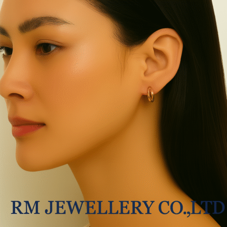 "Close-up profile of a woman wearing small, smooth, polished rose gold or gold huggie hoop earrings.