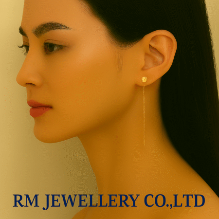 "Close-up profile of a woman wearing long, delicate gold-tone threader or drop chain earrings, originating from a small floral or circular stud at the earlobe.