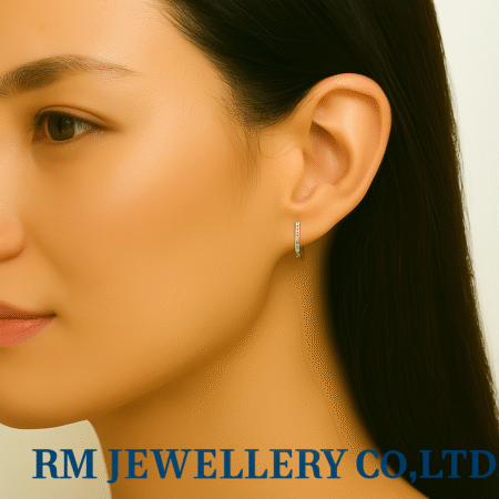 "Close-up profile of a woman wearing tiny, silver-tone pave huggie hoop earrings. The stones line the front edge of the small hoop.