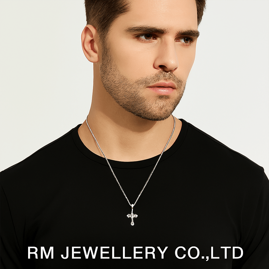 "Man wearing a silver-tone necklace with a small, detailed cross pendant hanging from a fine chain on a black shirt