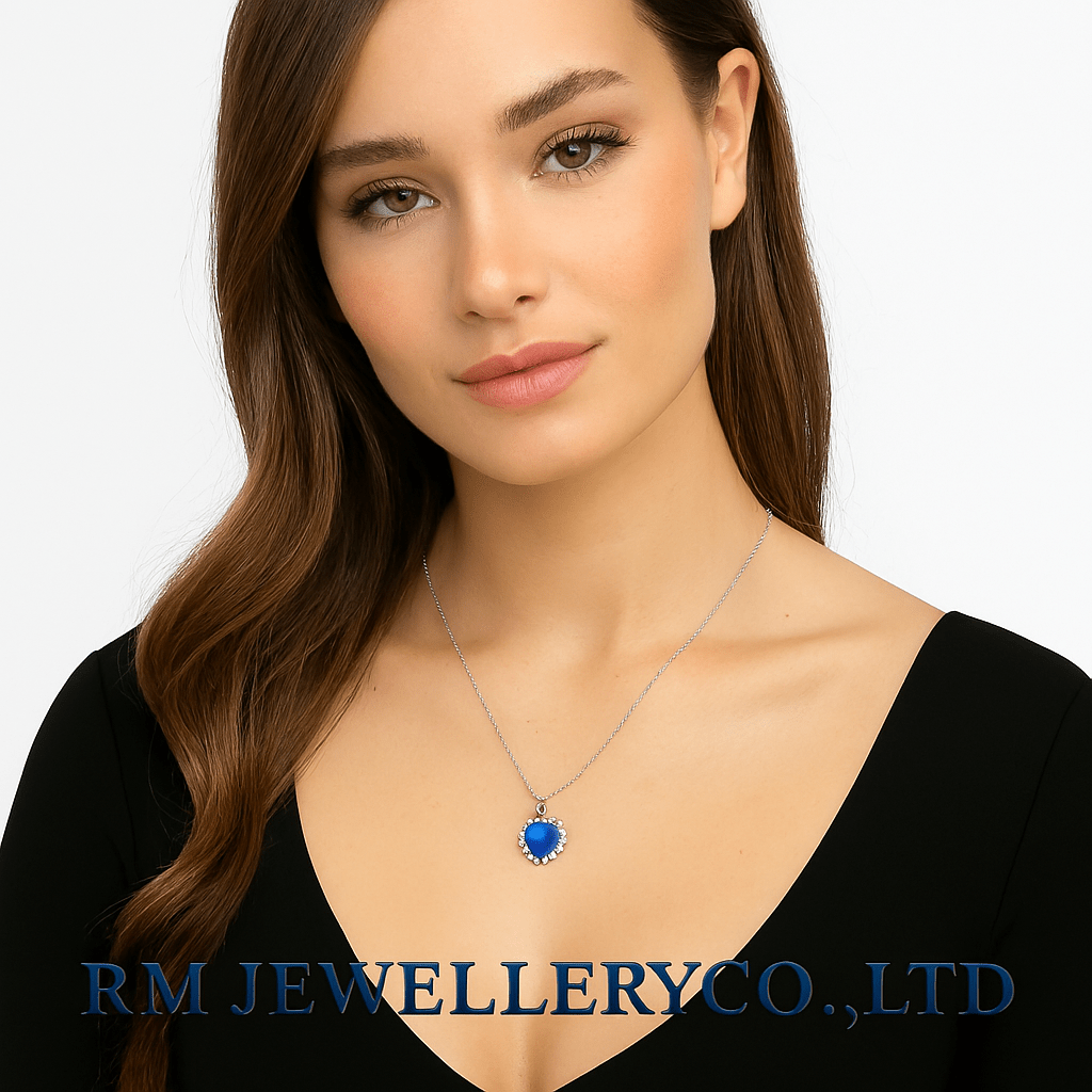 "Woman wearing a silver chain necklace with a large, heart-shaped, deep blue pendant surrounded by small clear stones on a white background. The text 'RM JEWELLERY CO., LTD' is visible at the bottom."