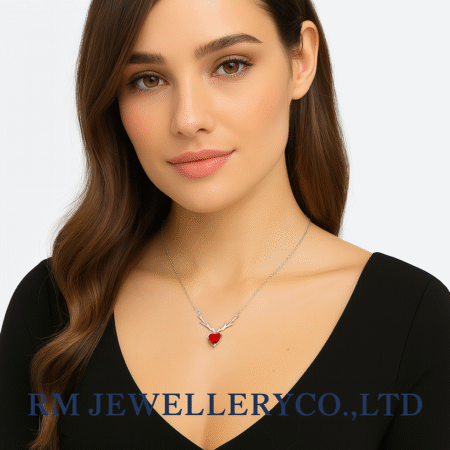 Woman wearing a silver necklace featuring a small, vibrant red heart pendant flanked by silver antler or branch-like details. The image has the 'RM JEWELLERY CO., LTD' watermark."