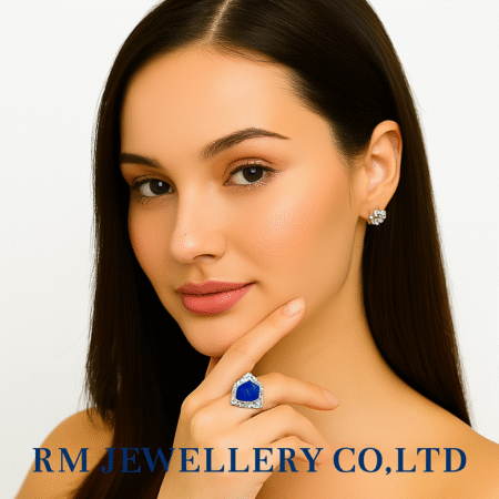 "Close-up of a woman wearing a striking cocktail ring featuring a large, vibrant blue pear-shaped gemstone surrounded by a sparkling halo of clear stones. The image is watermarked with 'RM JEWELLERY CO., LTD'."